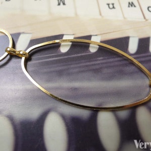 May include: Gold chain necklace with oval and round links. The chain is on a textured surface.