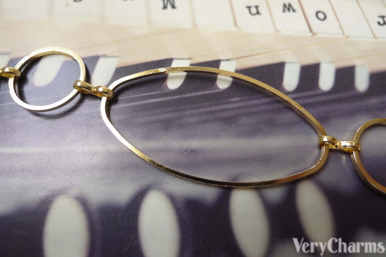 May include: Gold chain necklace with oval and round links. The chain is on a textured surface.