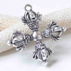 May include: Silver-toned metal pendant in the shape of a cross with intricate details. Each arm of the cross features a decorative design with a crown-like top.