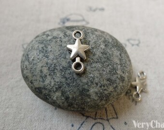 May include: Silver star charm with two jump rings. The charm is on a gray stone.