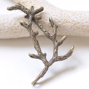 May include: A pair of antique bronze metal branches with a textured surface. The branches are connected at the base and have several smaller branches extending out. The branches are perfect for adding a rustic touch to jewelry making or other craft projects.