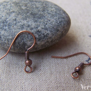 May include: Two copper earring hooks with a small ball at the end of each hook.