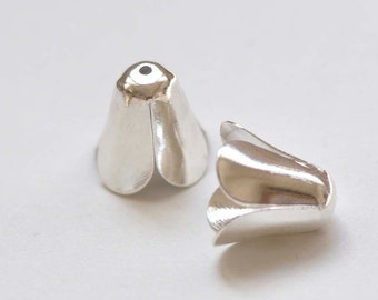 以下が含まれることがあります： 花の形をした銀色の金属製のビーズキャップが2つ。キャップはコードや紐の端を覆うように設計されています。
