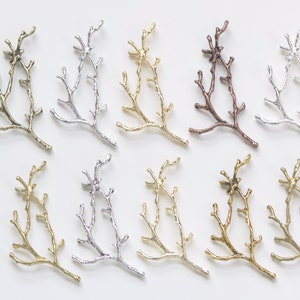 May include: Twelve metal twig branches in various finishes, including gold, silver, and copper. The branches are arranged in two rows of six, with each branch having a unique shape and texture.