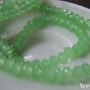 May include: A strand of light green faceted glass beads. The beads are translucent and have a slightly frosted finish.