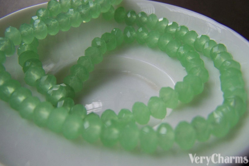May include: A strand of light green faceted glass beads. The beads are translucent and have a slightly frosted finish.