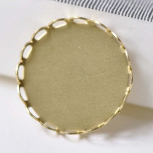 May include: A gold-coloured metal tray with a scalloped edge. The tray is round and has a smooth, flat surface.