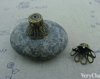 Puede incluir: Dos tapas de extremo decorativas de metal dorado antiguo para la elaboración de joyas. Las tapas de extremo tienen un diseño festoneado con un pequeño agujero en el centro.