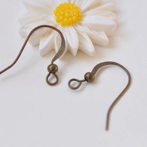 Puede incluir: Dos ganchos para pendientes de bronce con una pequeña cuenta redonda en la parte superior de cada gancho.