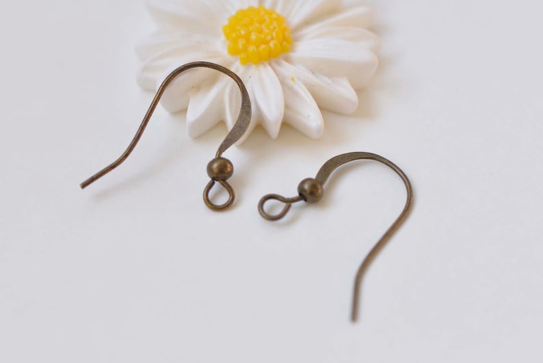 May include: Two bronze earring hooks with a small round bead at the top of each hook.