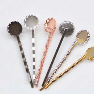 May include: Six hair clips with different colored metal settings and decorative edges. The clips are all the same size and shape, and they are arranged in a fan shape.