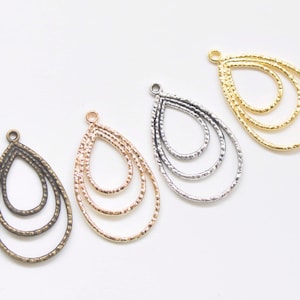 May include: Four teardrop-shaped metal earring blanks with a hammered texture. The blanks are in gold, silver, bronze, and rose gold.
