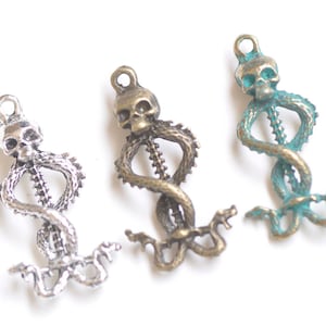 May include: Three silver, bronze, and turquoise snake charms with a skull at the top. The snake is coiled in a heart shape.