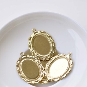 Peut inclure: Trois cadres ovales en m&eacute;tal dor&eacute; avec des bords orn&eacute;s. Les cadres sont sur une surface blanche.