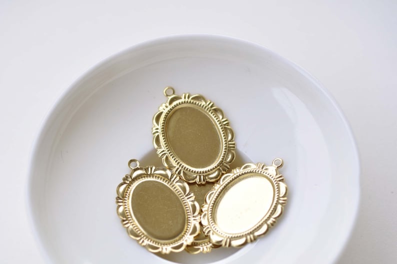 Peut inclure: Trois cadres ovales en m&eacute;tal dor&eacute; avec des bords orn&eacute;s. Les cadres sont sur une surface blanche.
