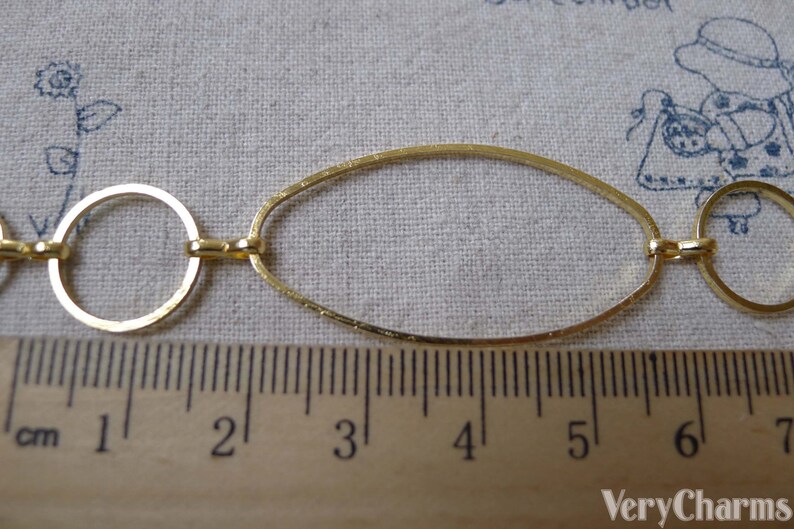 May include: Gold chain with oval and round links. The chain is measured against a ruler, showing it is approximately 5 inches long.