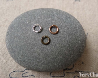 May include: Three jump rings in different finishes: silver, copper, and bronze. The rings are displayed on a gray stone.