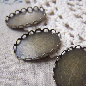 May include: Three oval-shaped metal settings with scalloped edges. The settings are made of a brass-coloured metal and are designed to hold a cameo or other decorative item.