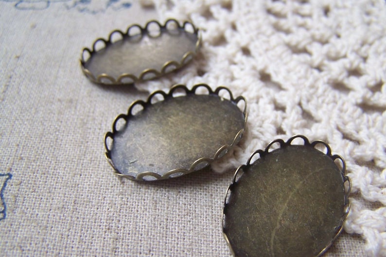May include: Three oval-shaped metal settings with scalloped edges. The settings are made of a brass-coloured metal and are designed to hold a cameo or other decorative item.
