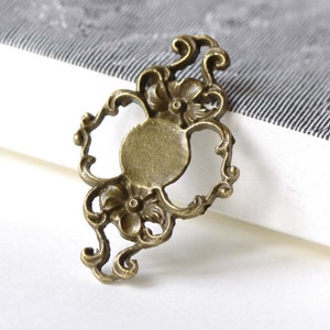 May include: A bronze-colored metal frame with a decorative floral design. The frame has a round opening in the center and is perfect for adding a touch of vintage charm to your crafts.