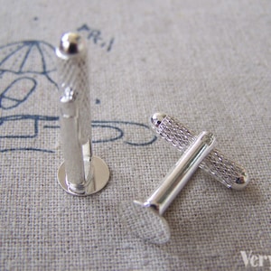 May include: A pair of silver cufflinks. One cufflink has a textured design and the other has a smooth surface.