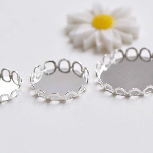 May include: Three silver-toned metal bezel settings for crafting jewellery. The bezels are round and have a scalloped edge. The bezels are different sizes.