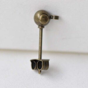 May include: A small, bronze-colored traffic light pendant with a round top and two red lights.