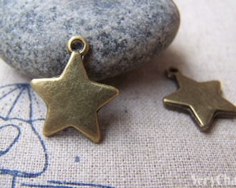 Peut inclure: Deux breloques en forme d'étoile de couleur bronze, avec une boucle en haut pour les suspendre. Les breloques sont à cinq branches et ont une surface légèrement texturée. Une breloque est mise au point, l'autre est floue.