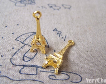 May include: Two gold-coloured Eiffel Tower charms. The charms are small and detailed, with a loop at the top for attaching to a necklace or bracelet.