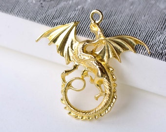 May include: A gold-colored metal dragon pendant with wings outstretched and a curled tail. The pendant has a loop at the top for attaching to a chain or cord.