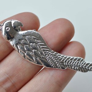 May include: Silver parrot charm with detailed wings and a loop for attaching to jewelry or crafts.