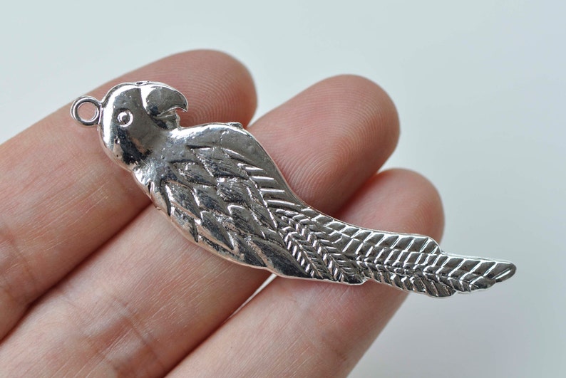 May include: Silver parrot charm with detailed wings and a loop for attaching to jewelry or crafts.