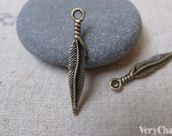 Puede incluir: Dos encantos de plumas de bronce antiguo con un bucle en la parte superior. Los encantos miden aproximadamente 5 cm de largo y tienen un diseño de pluma detallado.