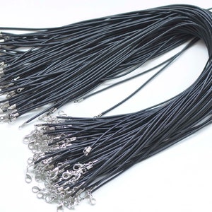 Puede incluir: Un conjunto de collares de cordón negro con cierres y extremos plateados. Los cordones están tejidos de forma apretada y parecen estar hechos de un material duradero. Los cierres son de tipo mosquetón.