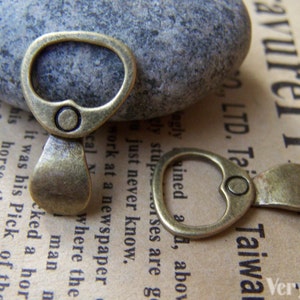 May include: Two antique gold-toned bottle opener charms. The charms are made of metal and have a ring at the top for attaching to a necklace or bracelet.