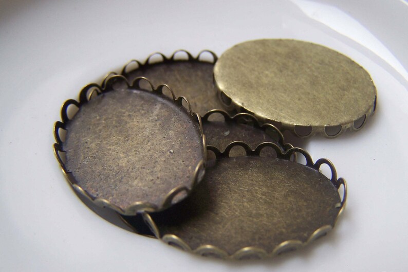 May include: Three oval-shaped metal settings with scalloped edges. The settings are made of brass and have a vintage, antique look.
