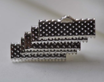 May include: A stack of silver metal clasps with a textured surface. The clasps are designed to be used for attaching straps or cords to a variety of items.