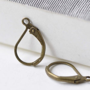 May include: Two antique gold-toned earring hooks. The hooks are made of metal and have a teardrop shape.