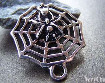 May include: Silver charm featuring a black spider in a web. The charm has a loop for attaching to a bracelet or necklace.