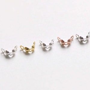 May include: Four silver, gold, and rose gold metal bead caps. Each cap is shaped like a half-circle with five small, rounded points.
