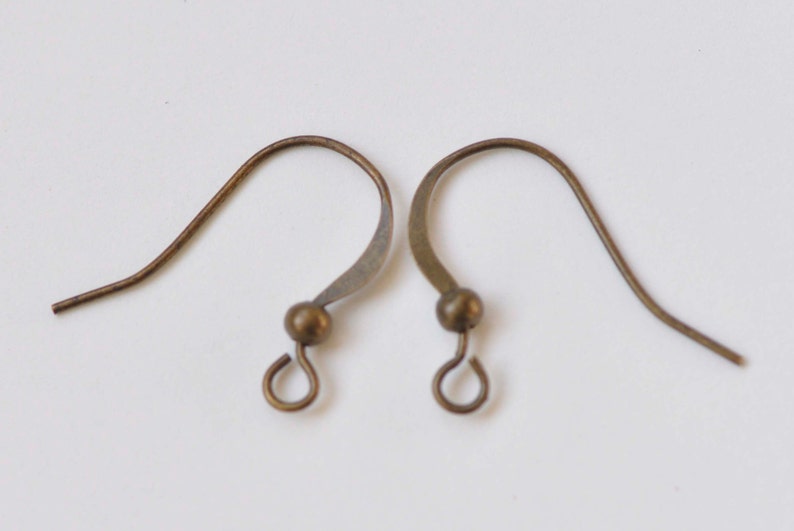 May include: Two bronze-colored earring hooks with a small ball at the top and a loop at the bottom.
