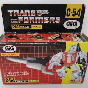 May include: A red, white, and black toy robot in airplane mode. The robot is labeled "C-54 Aerialbot Tornado" and is part of the "Transformers" toy line. The box is labeled "Gig" and "Transformer".