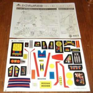 May include: A sheet of stickers with various colored and black and white designs. The stickers include the words "MB-1", "MB-2", and "Micro Man".