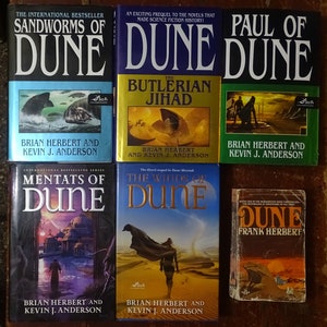 May include: A collection of ten science fiction paperback books featuring the Dune series by Frank Herbert and Brian Herbert. The books are arranged in a vertical stack with the titles visible. The books are all different colors and have different covers.
