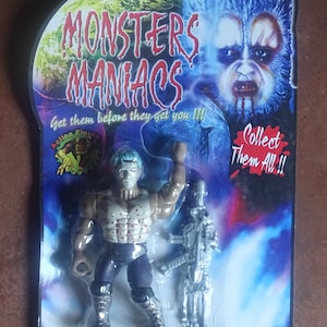 Puede incluir: Una figura de acción empaquetada de la serie "Monsters Maniacs". La figura es un humanoide musculoso con una cabeza azul y un arma plateada. El embalaje presenta un gráfico de monstruo y el texto "Get them before they get you!!!" y "Collect Them All!!".