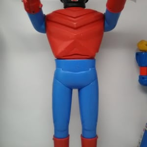 May include: A red and blue plastic action figure of a superhero with a silver helmet and a raised fist.