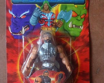 Puede incluir: Figura de acción vintage de un guerrero musculoso, empaquetada en una tarjeta roja y azul. El embalaje presenta el texto "FUERZA-T" e ilustraciones de personajes. La figura está en una burbuja de plástico transparente.