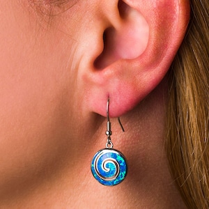 Puede incluir: Un par de pendientes de plata con un diseño de espiral de ópalo azul.