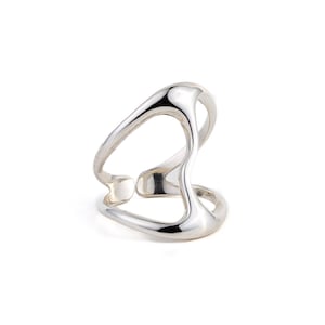 May include: A silver ring with a unique, abstract design. The ring is made of a single piece of metal that is bent and twisted into a shape that resembles a wave or a flowing liquid.