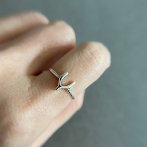 May include: A silver ring with a simple antler design.